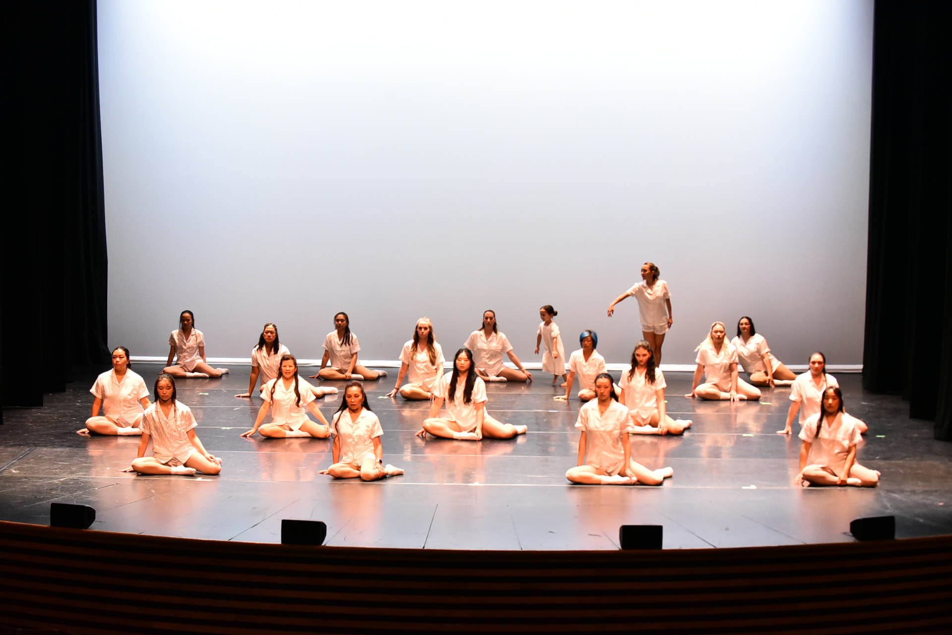 A large ensemble seated across the stage in white