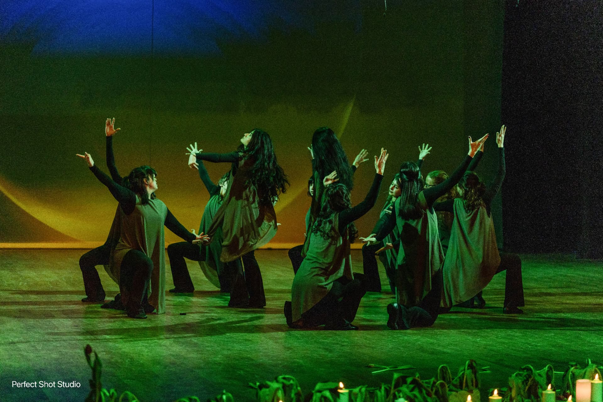 The ensemble kneeling in green and gold light