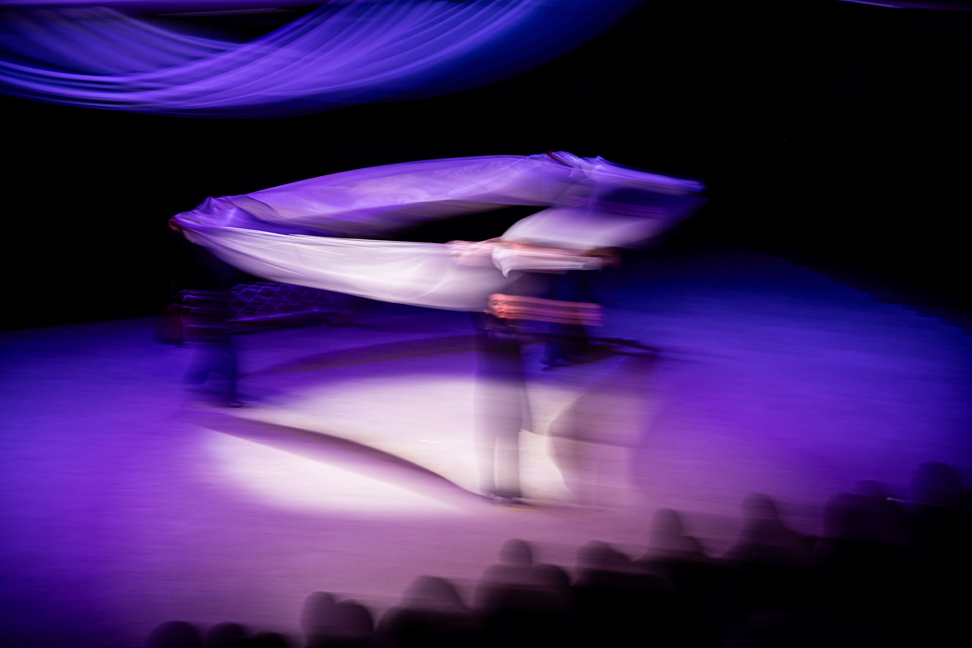 Dancers in flowing motion under purple light